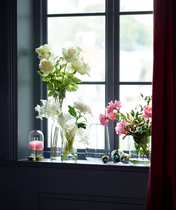 IKEA BERÄKNA vases filled with pink and white flowers on a sunlit window sill.
