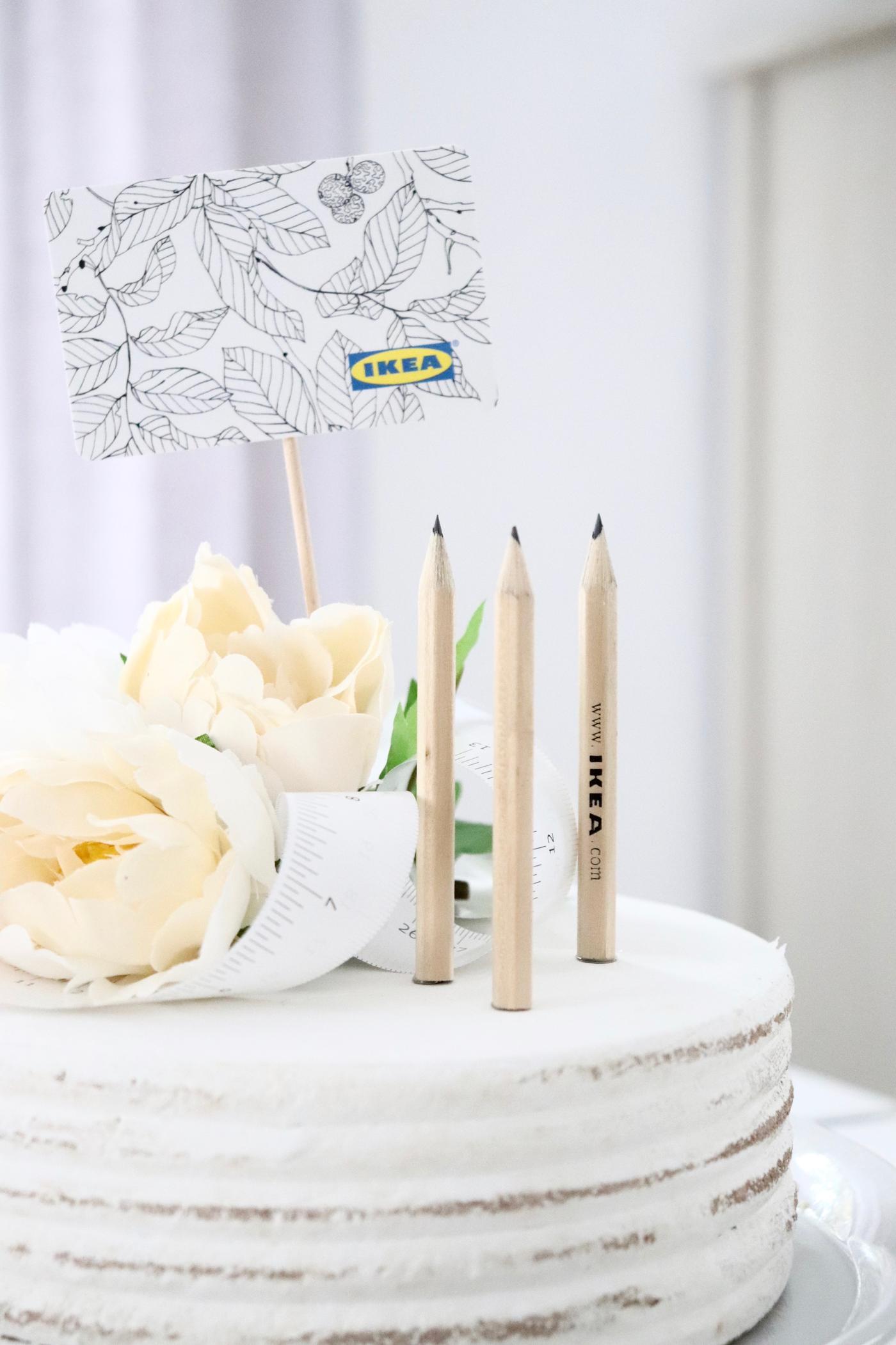 IKEA Bleistifte und eine IKEA Geschenkkarte wurden auf einer weißen Torte angerichtet.