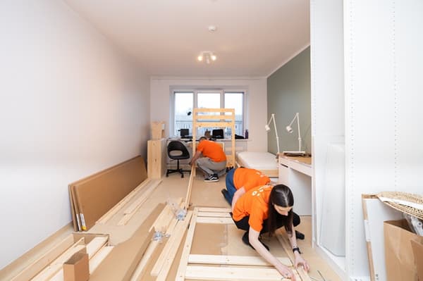 IKEA brīvprātīgo komanda montē mēbeles un iekārto telpu.