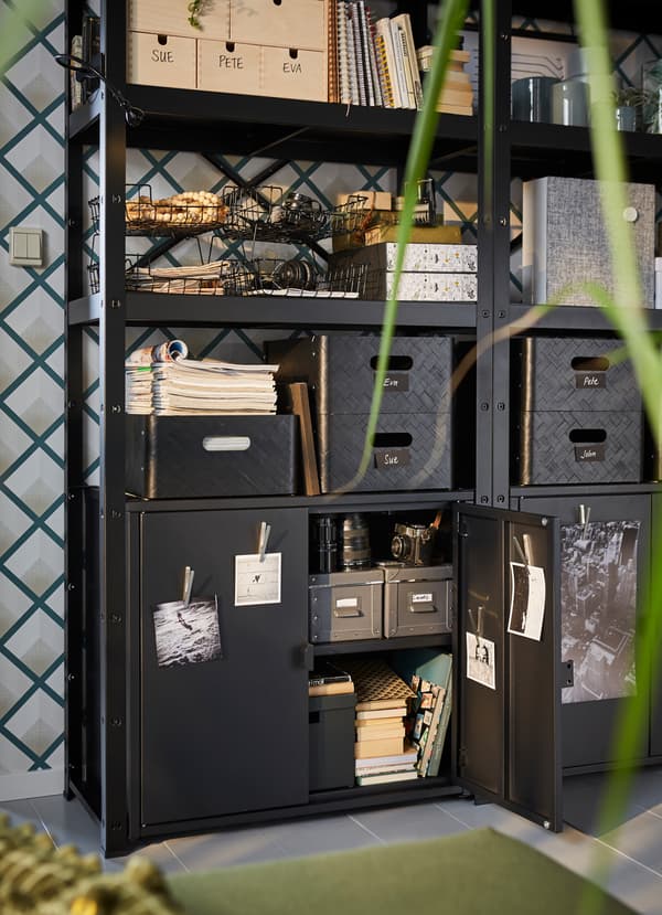 IKEA BROR powder-coated galvanized steel black shelving unit, with boxes and organisers placed on its 3 shelves.