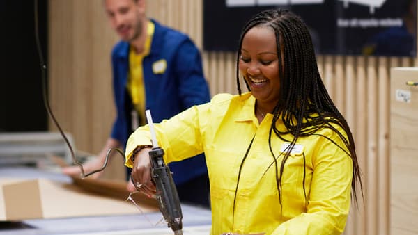 IKEA co-worker in a yellow shirt sealing a package with a hot glue gun.