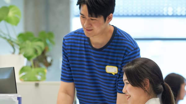 IKEA co-worker in blue striped uniform at a desk, supporting a customer in the store.