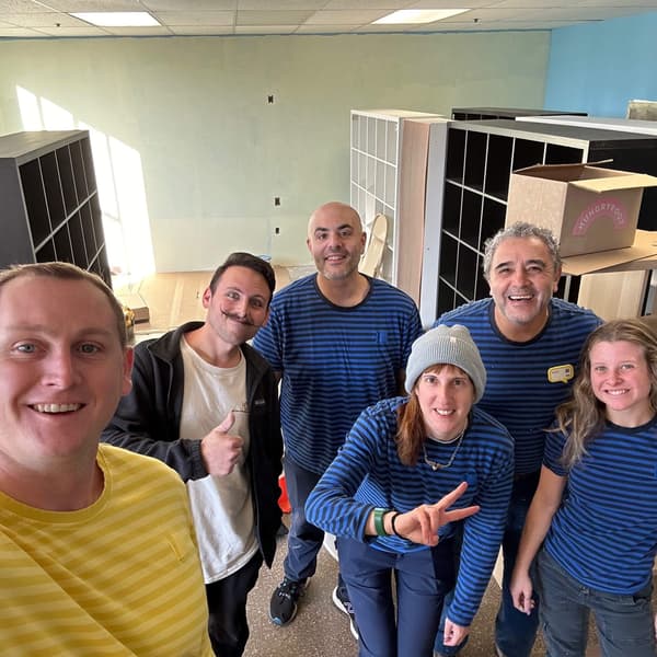 IKEA co-workers smiling with built furniture behind them.