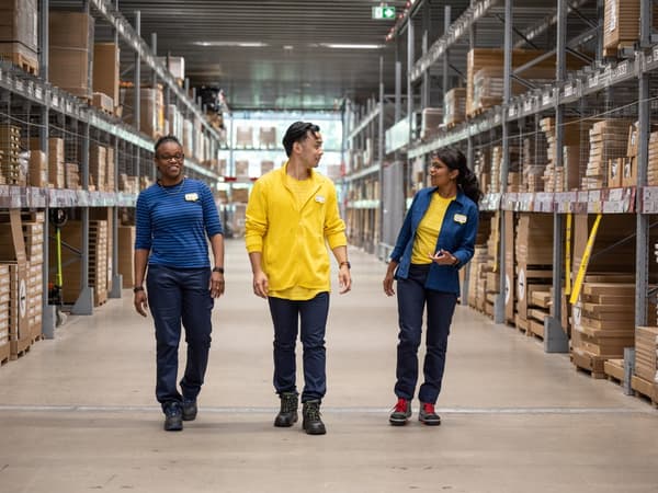 IKEA co-workers walk aisle of self-serve warehouse.