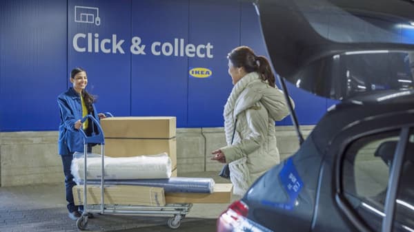 IKEA coworker pushing flat cart with furniture for a customer to load into the car.