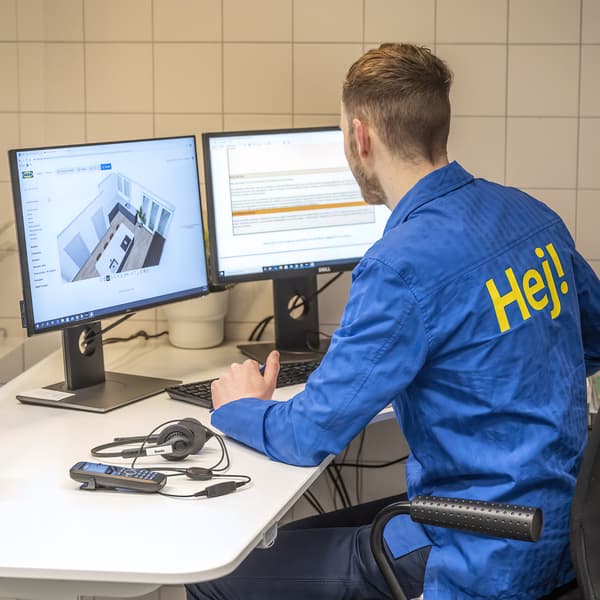 IKEA coworker sits at white desk in front of two desktop monitors planning a room