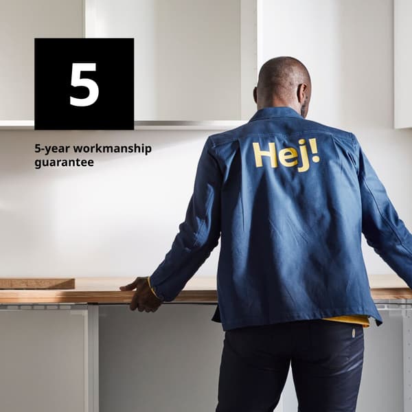 IKEA coworker standing in front of a kitchen display on the cabinets and worktop in store
