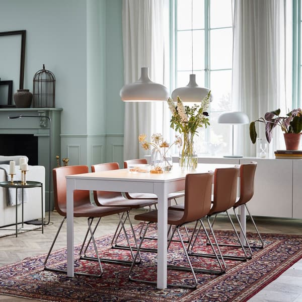 IKEA EKEDALEN white extendable table and BERNHARD brown leather seats in a modern open space dining area.