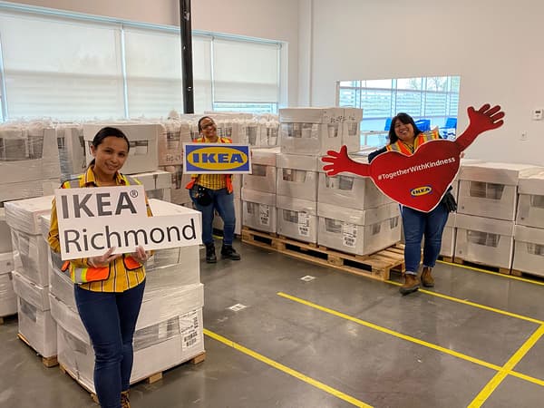 IKEA employees posing with stacked white boxes of donated bedding.