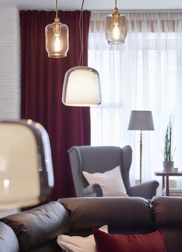 IKEA EVEDAL hanging pendant lamps arranged at different heights above a dark leather brown sofa.