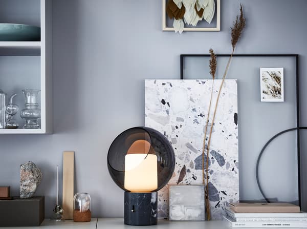 IKEA EVEDAL kerek fekete asztali lámpa, keretekkel és alkotásokkal az asztallapon.