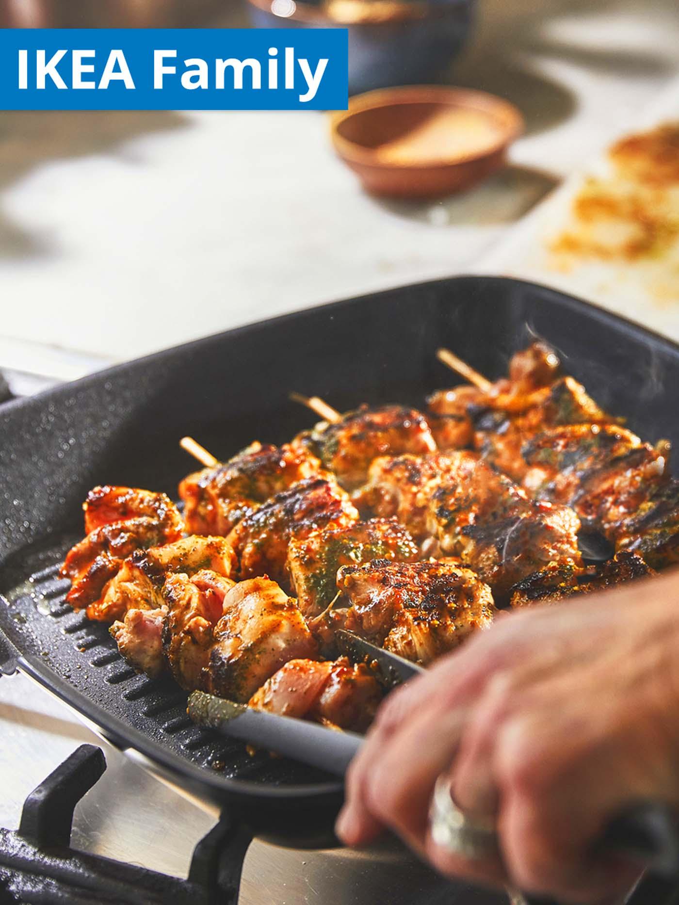 IKEA Family offer. Meat kebabs being grilled on a black HEMLAGAD grill pan.