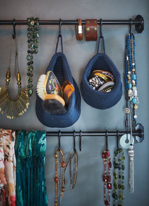 IKEA FINTORP black rails mounted to a wall, hanging hang jewelry and hair accessories stored in NORDRANA blue weaved baskets.