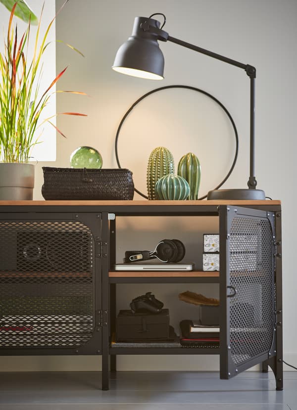 IKEA FJÄLLBO black TV bench, made of metal and a solid wood surface. The mesh metal cabinet doors allow electronic signals to pass through.