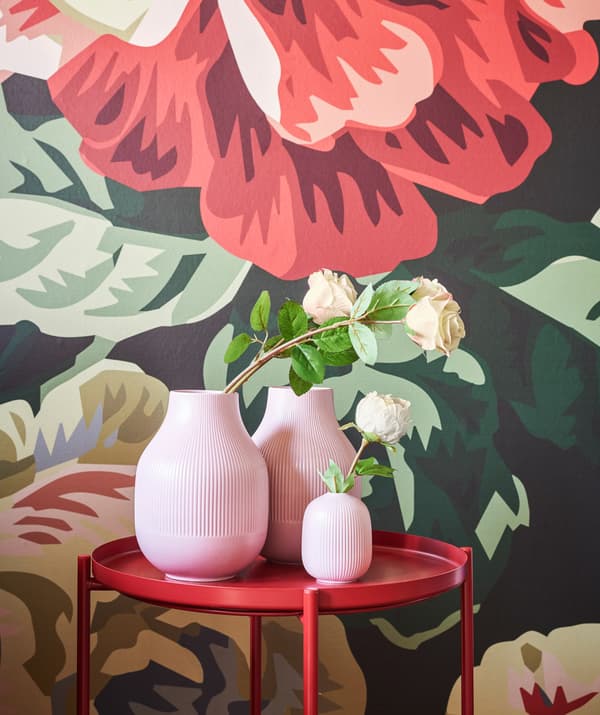 IKEA GRADVIS vases on a red side table in front of the bold floral wallpaper in the background.