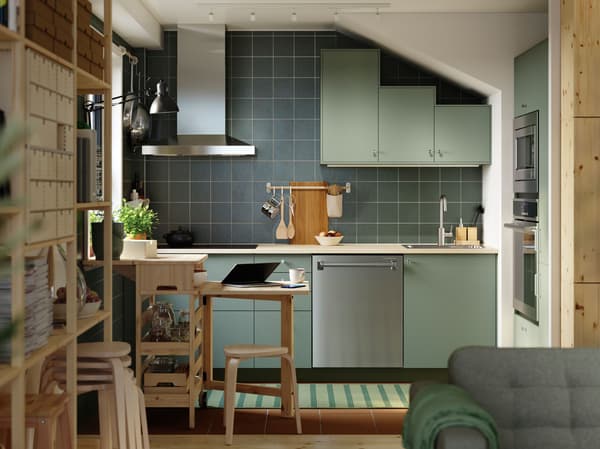 IKEA Green kitchen with a natural wood counter and a natural wood table, chair and shelving unit.
