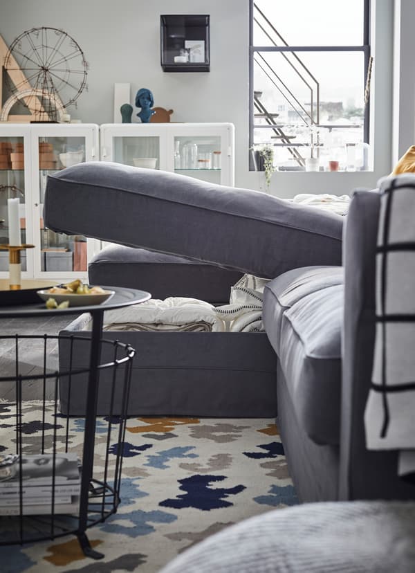 IKEA GRÖNLID grey sofa unit, with cushioned storage compartment lifted open to reveal bedding.