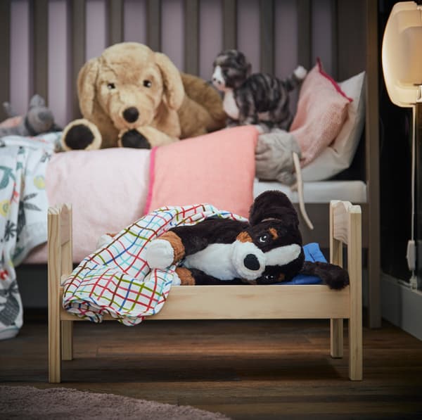 IKEA HOPPIG soft dog toys in a small bed.