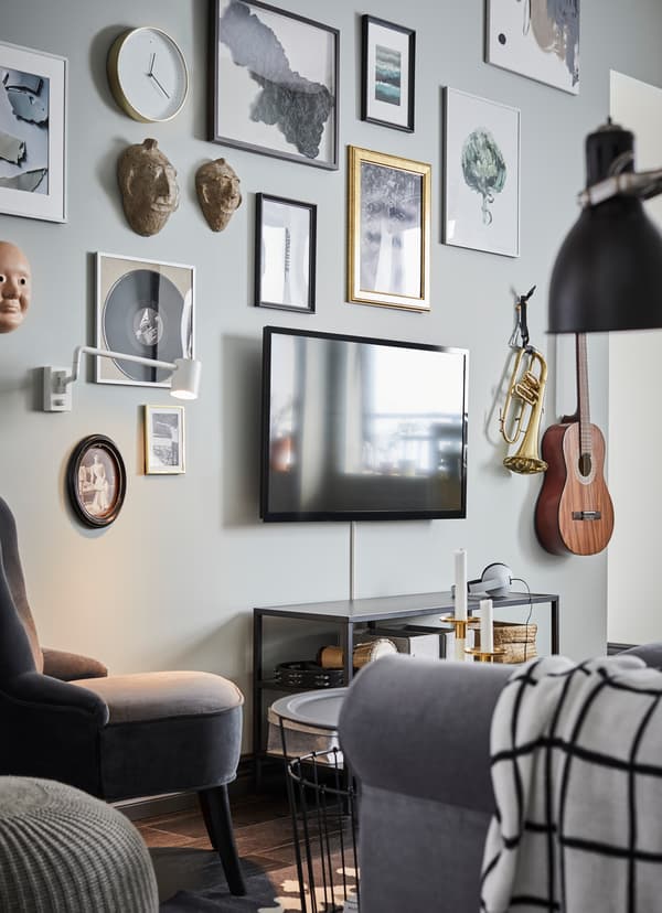 IKEA HOVSTA black picture frames and mounted musical instruments arranged around a TV.