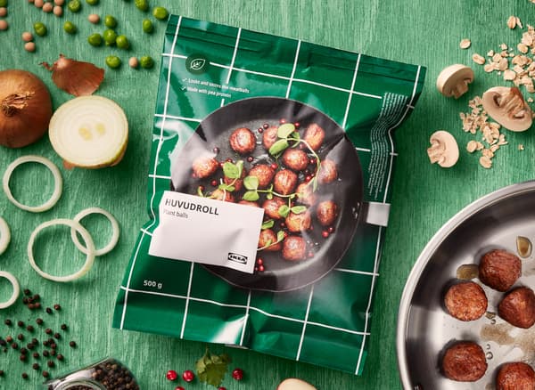 그린 색상의 원목 상판 위에 놓인 IKEA HUVUDROLL 후부드롤 플랜트볼. 다양한 재료가 음식을 둘러싸고 있습니다.