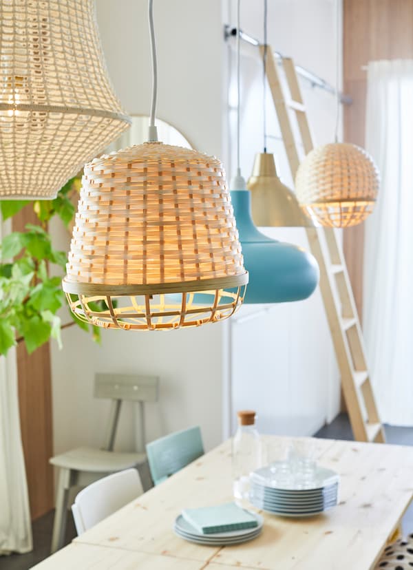 IKEA INDUSTRIELL pendant lamp woven from beige fibres, hanging over a wooden dining table.