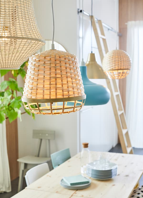 IKEA INDUSTRIELL pendant lamp woven with beige fibres, hanging over a wooden dining table.
