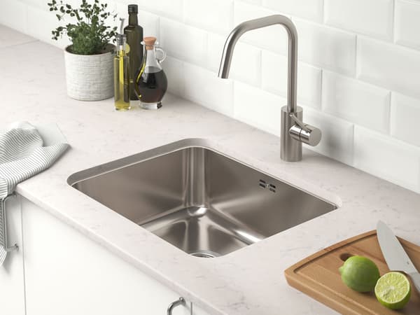 IKEA KÜche mit weißen Fronten hellgrauer Arbeitsplatte und einem silber Waschbecken.