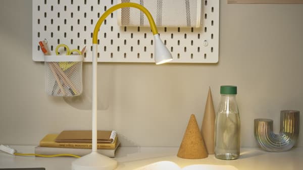 IKEA lamp on a desk with organizational items on the surface as well as wall organization