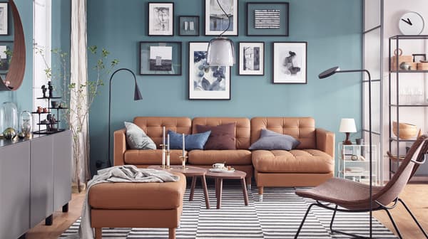 IKEA LANDSKRONA goudbruine lederen bank met lange ligstoel en voetenbank, tegen een theemuur in een woonkamer.