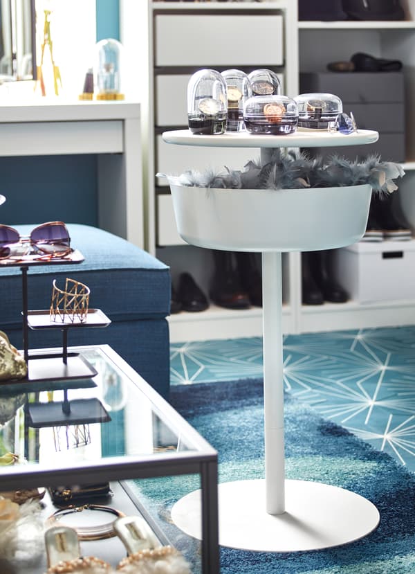 IKEA LIERSKOGEN circular white rounded bedside table, with a deep shelf holding a feather scarf and accessories.