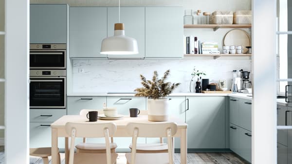 IKEA light blue modern kitchen with white worktops and wood flooring