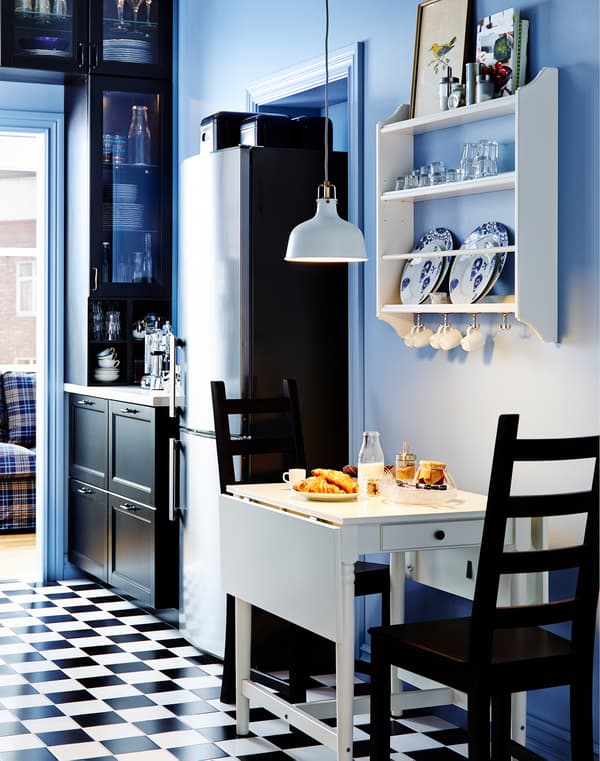 IKEA mahai txiki zabalgarria bi aulkirekin. Plateretarako apalategia goiko horman.