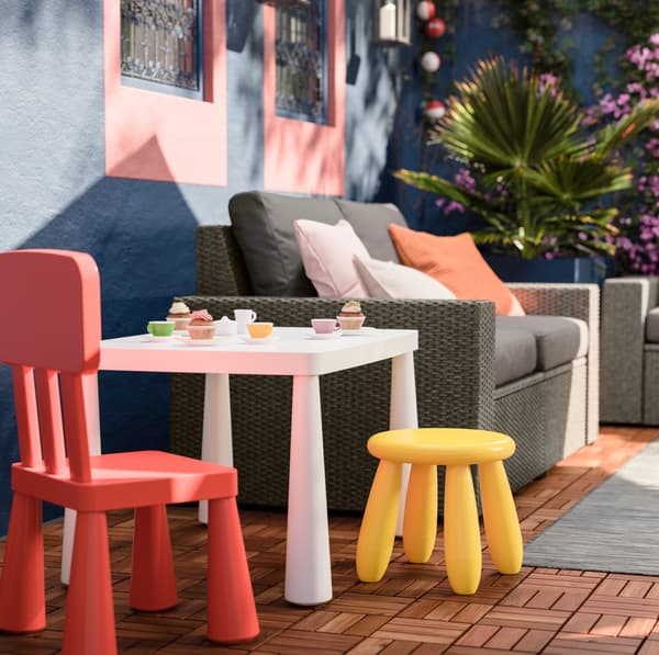 IKEA MAMMUT outdoor children’s furniture including a low yellow stool, red chair and chunky white recycled plastic table.