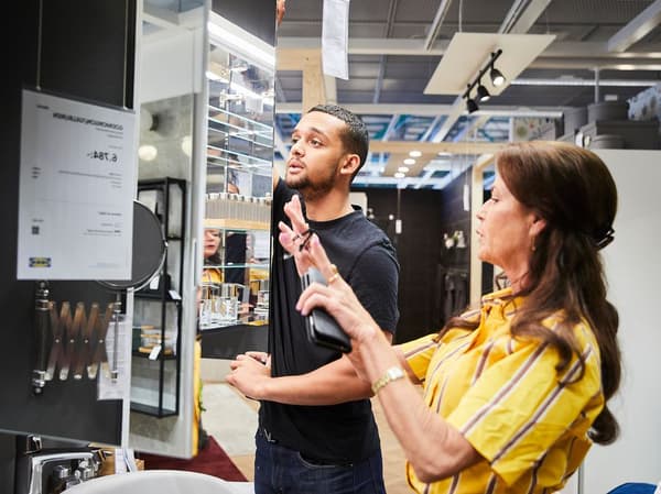 IKEA medarbetare hjälps åt att hänga upp ett spegelskåp