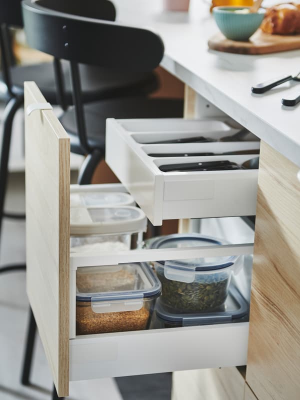 IKEA METOD cabinets with ASKERSUND smooth wood ash-effect fronts with two open drawers used for storing dry goods.