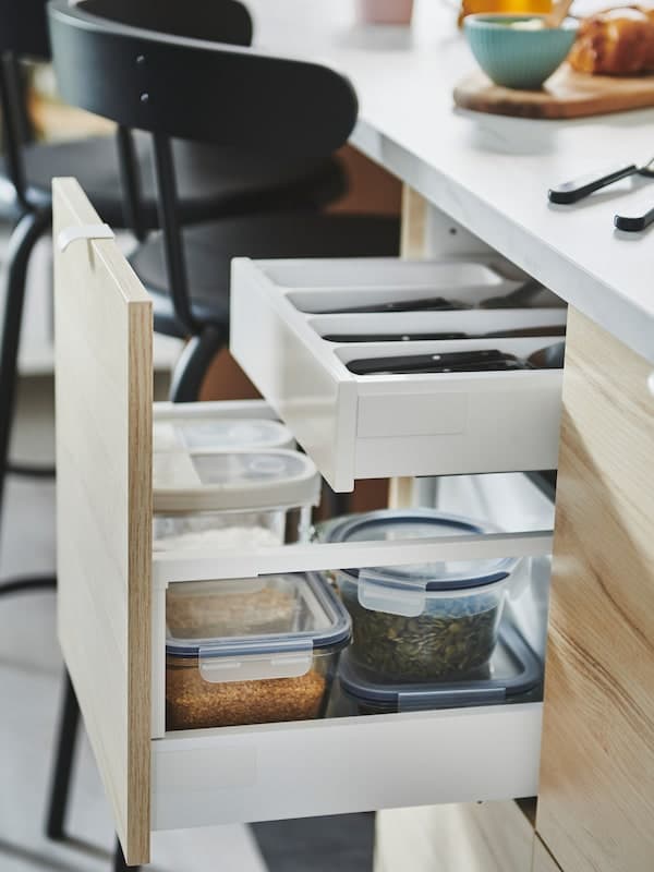 IKEA METOD cabinets with ASKERSUND smooth wood ash-effect fronts with two open drawers used for storing dry goods.