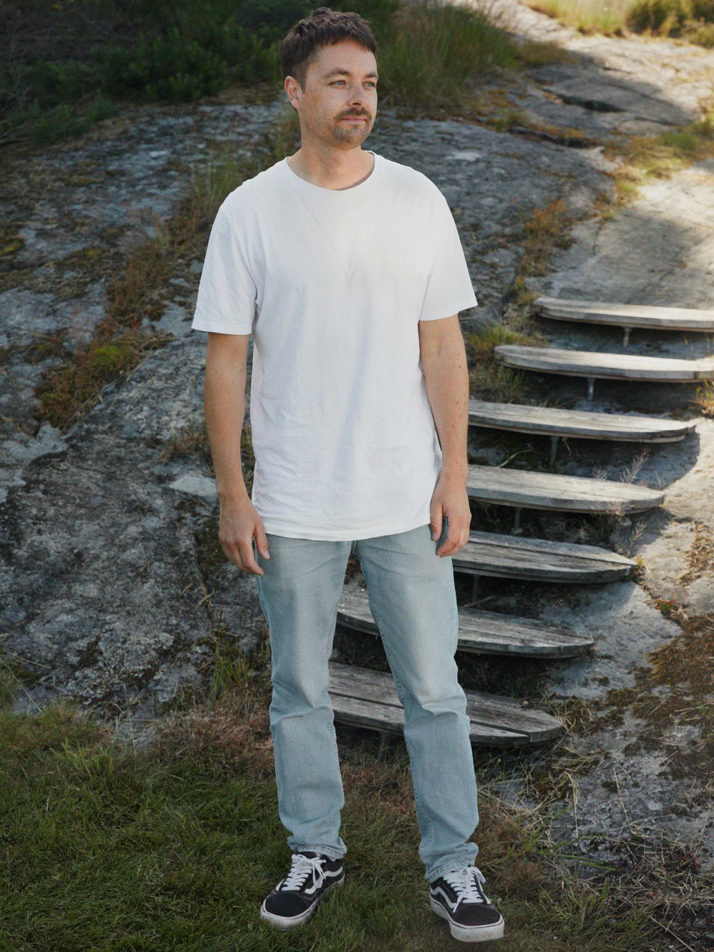 나무 계단 발치, 돌이 많은 언덕 앞에 IKEA 디자이너 Mikael Axelsson이 서 있는 모습.