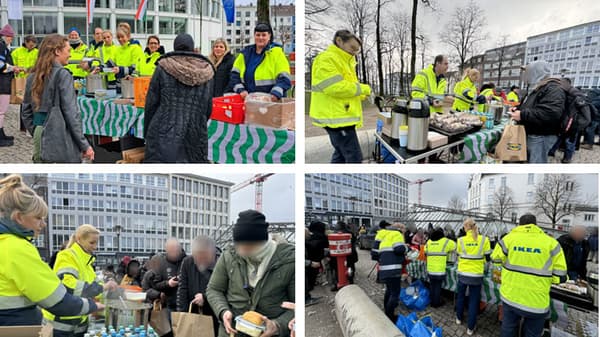 IKEA-Mitarbeitende in gelben Jacken organisieren eine Essensausgabe im Freien. Sie stehen hinter Tischen mit Lebensmitteln, Getränken und warmen Speisen und verteilen diese an wartende Menschen. Im Hintergrund sind moderne Gebäude und ein Baukran zu sehen.  