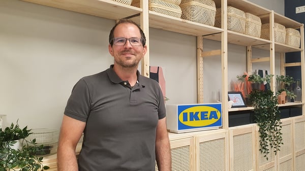 IKEA Mitarbeiter, der vor einem Regalhintergrund steht.