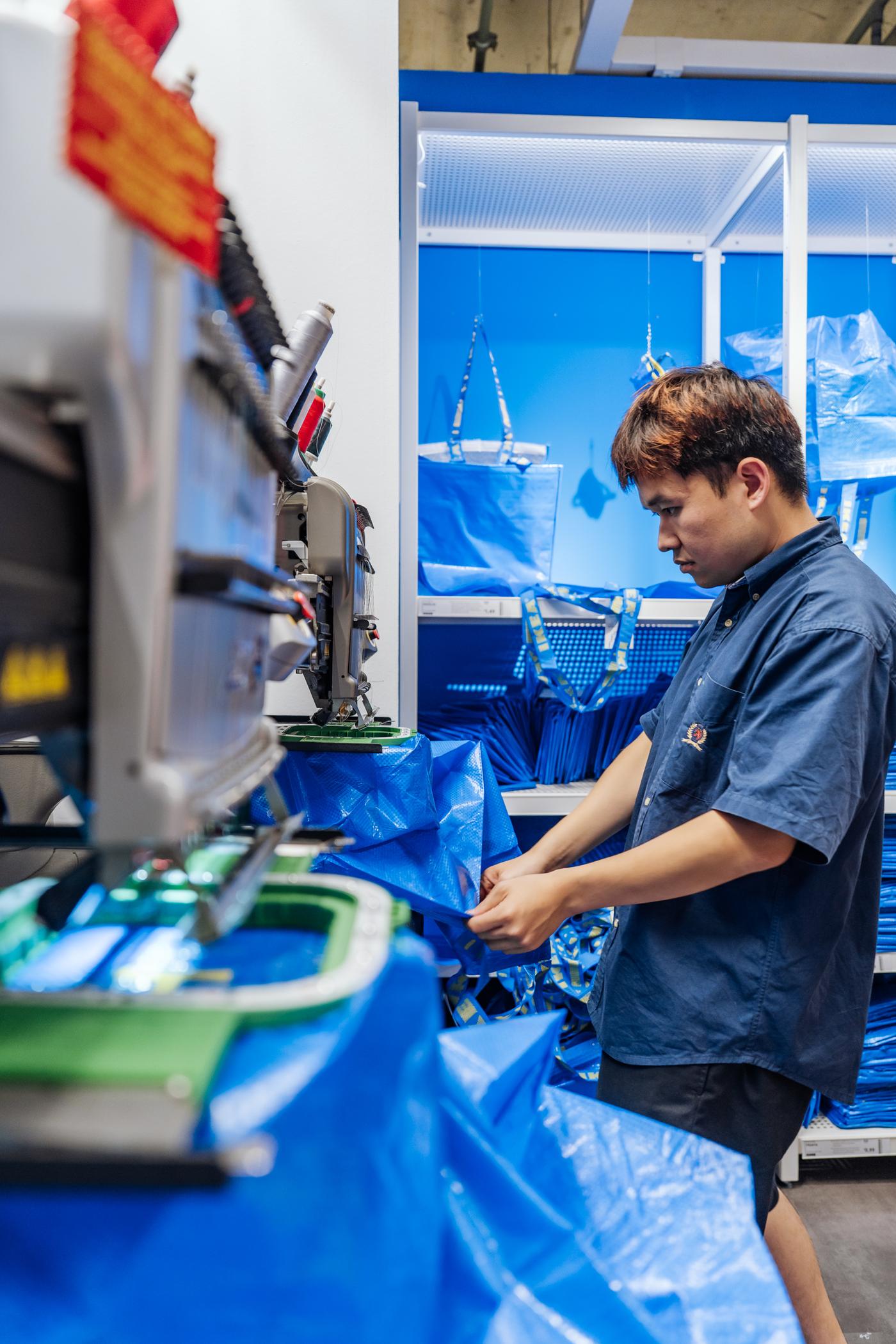 IKEA Mitarbeiter personalisiert eine blaue FRAKTA Tasche mit Buchstaben.