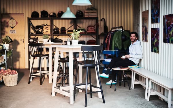 IKEA NORRÅKER light wood bar tables with high black bar chairs in a small farmhouse styled cafe setting.
