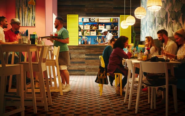 IKEA NORRÅKER white birch bar tables and birch bar stools in a colourful small restaurant setting with INDUSTRIELL bamboo woven pendant lamps.