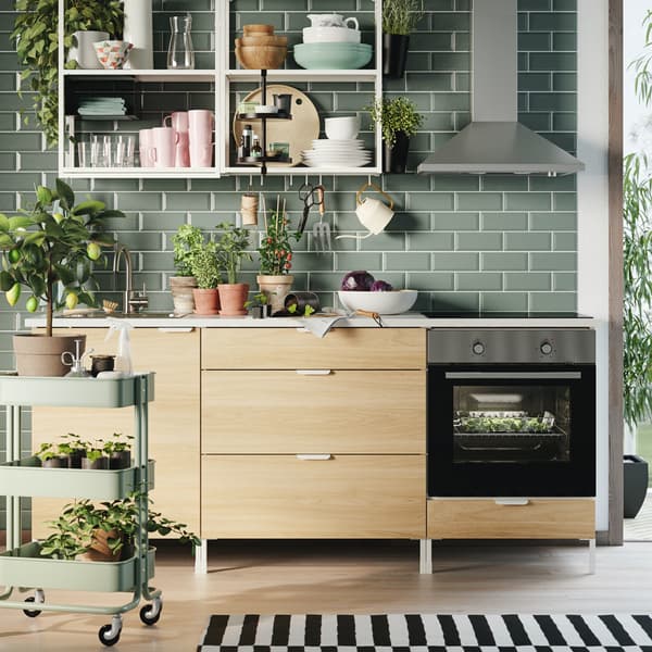 IKEA oak wood effect ENHET kitchen and white worktop with a green tiled wall and wood floor