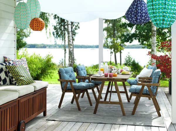 IKEA Outdoormöbel mit blauen Pölstern und einer SItzbank auf der Linken Seite. von der Decke Hängende Ballon Förmige Leuchten