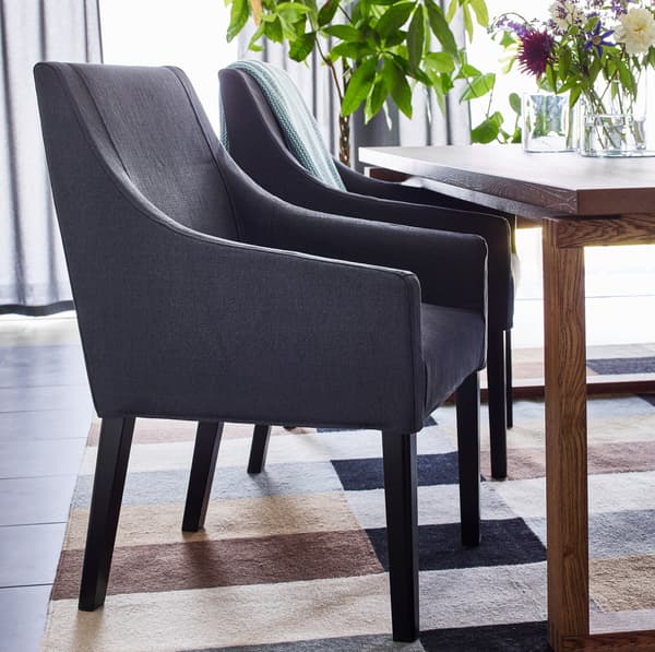 IKEA SAKARIAS dark grey dining chairs are designed with curved low armrests, and fit perfectly underneath MÖRBYLÅNGA oak veneer brown stained table.