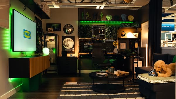 IKEA showroom featuring a modern home office with green accent lighting, desk setup, shelving, and lounge seating.