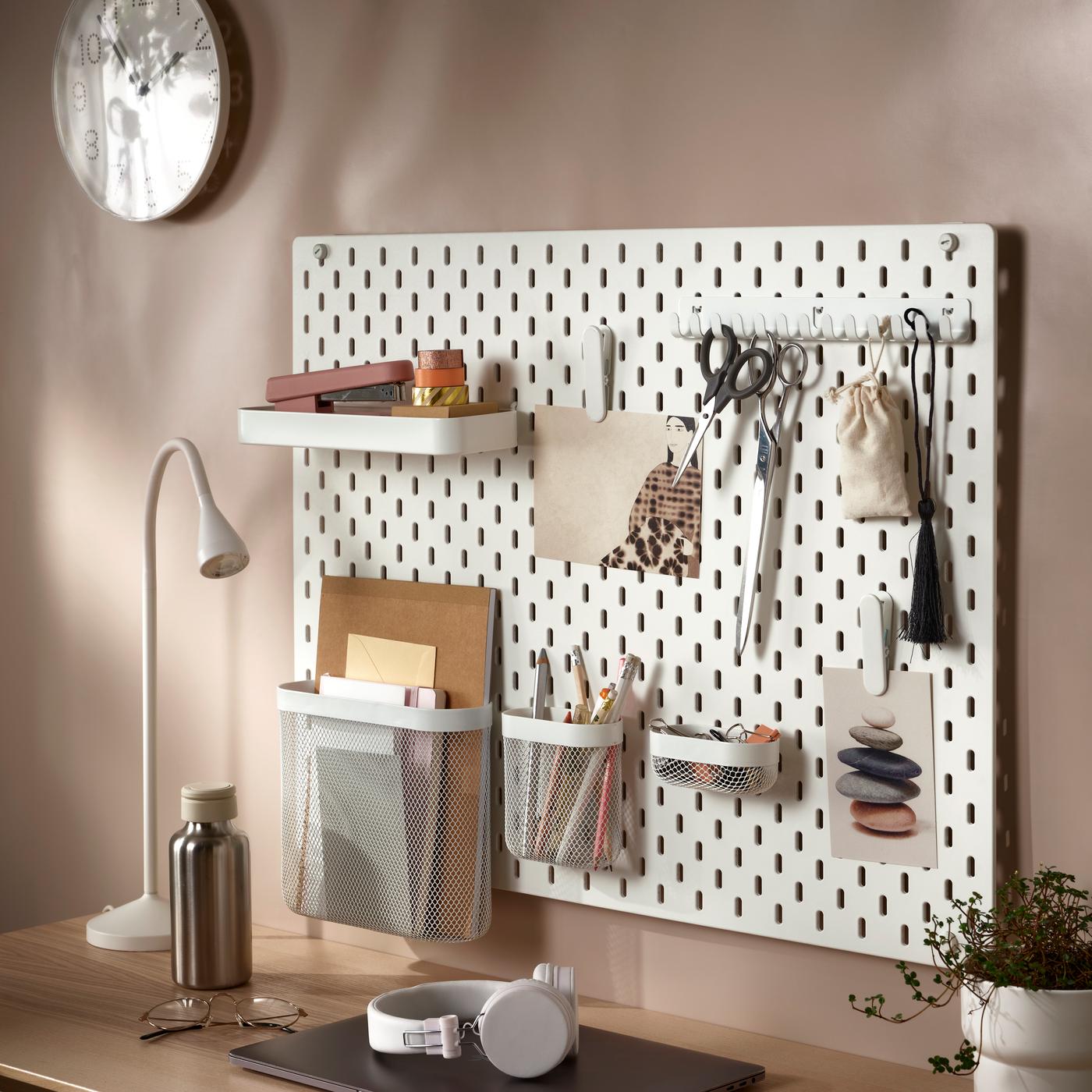 IKEA SKÅDIS bela perforirana ploča s različito obojenim posudama u kojima su šareni flomasteri, spajalice i traka.