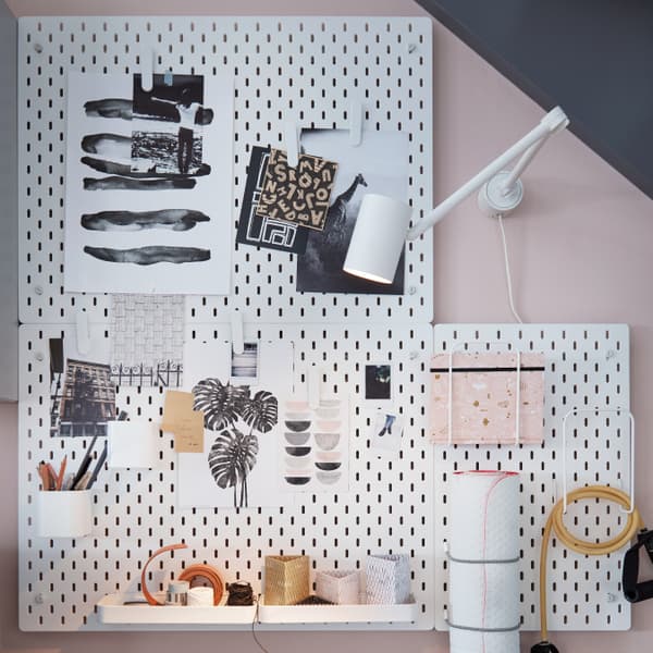 IKEA SKÅDIS white pegboard in an blue and pink pastel wall with storage papers, pens and some gym objects. 