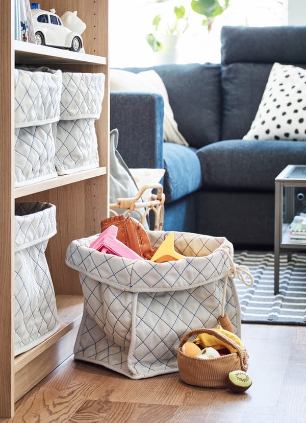 IKEA SKUBBARE soft fabric baskets holding children's toys at the base of the bookcase.