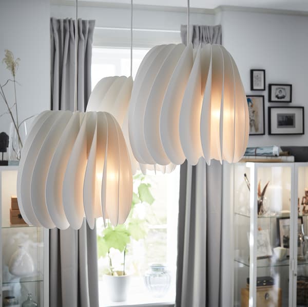 IKEA SKYMNINGEN white pendant lamps emitting soft light from a white slatted lampshade.